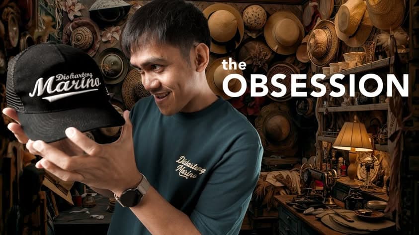 A man holding a Diskarteng Marino cap in a hat-filled studio.